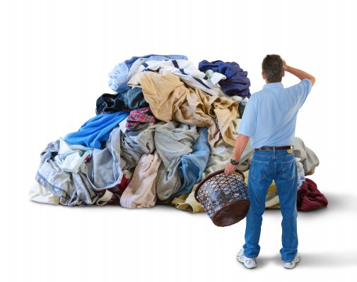 man holding laundry basket piles of laundry washing machines